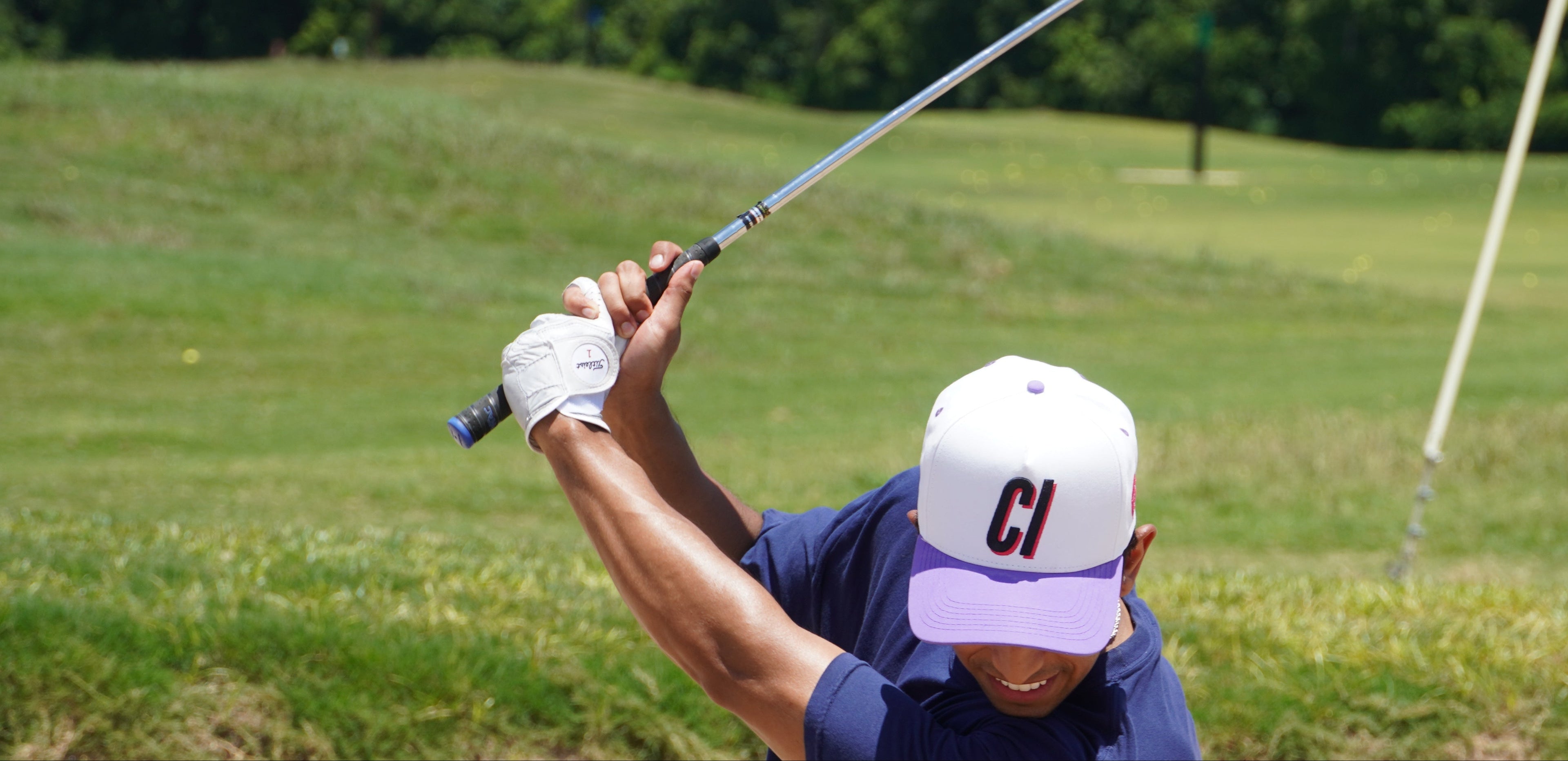 Person playing golf on a course with trees in the background
